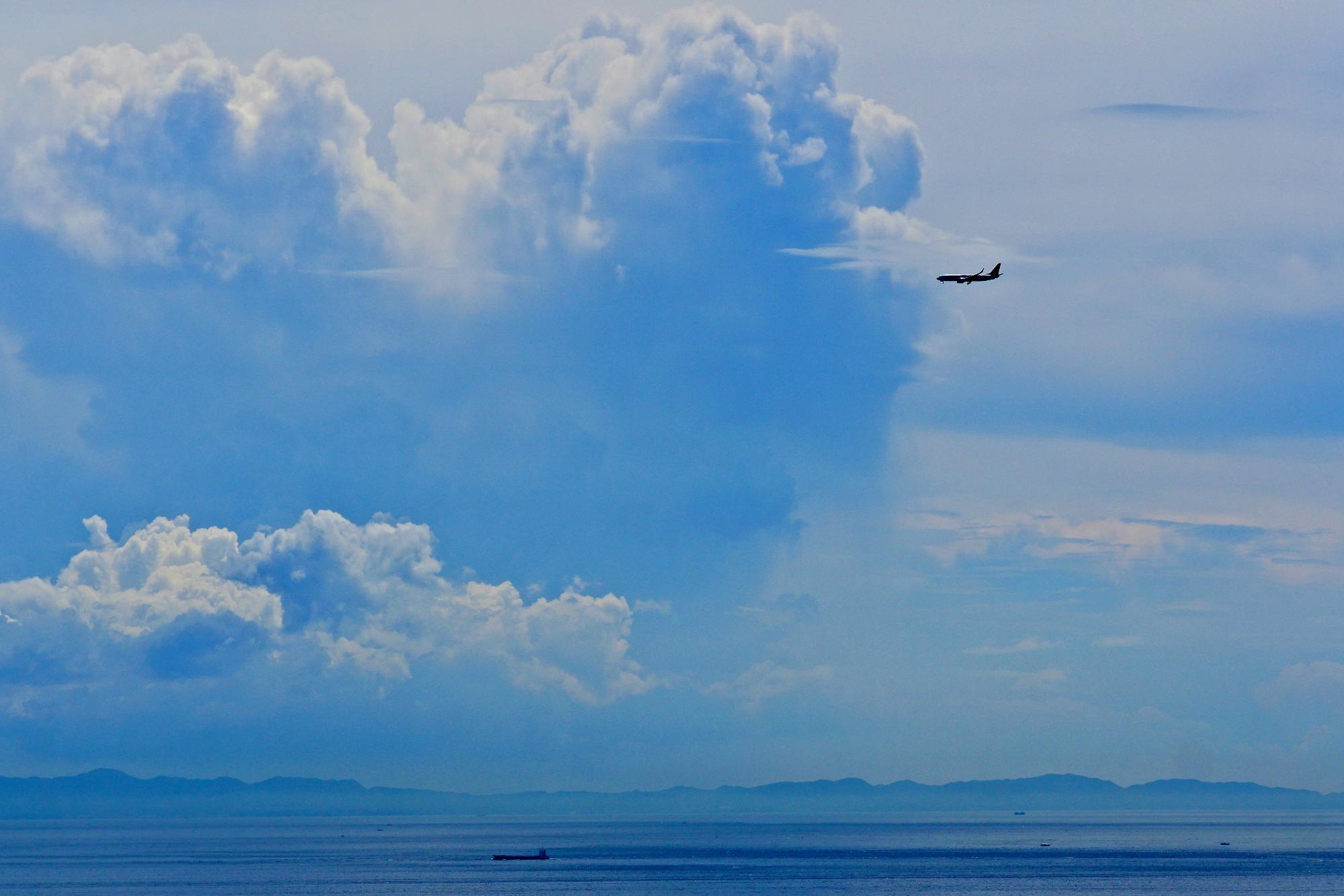 湖面の上空を覆う積乱雲に飛んでいく飛行機を捉えた写真