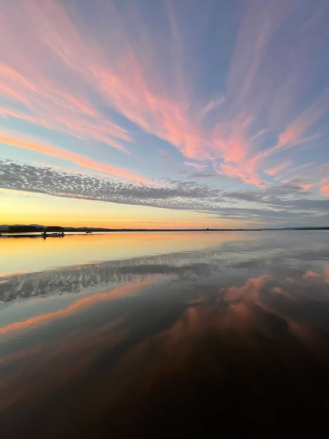 オーロラのような夕やけ空が湖面にそのまま映っている様子を捉えた写真