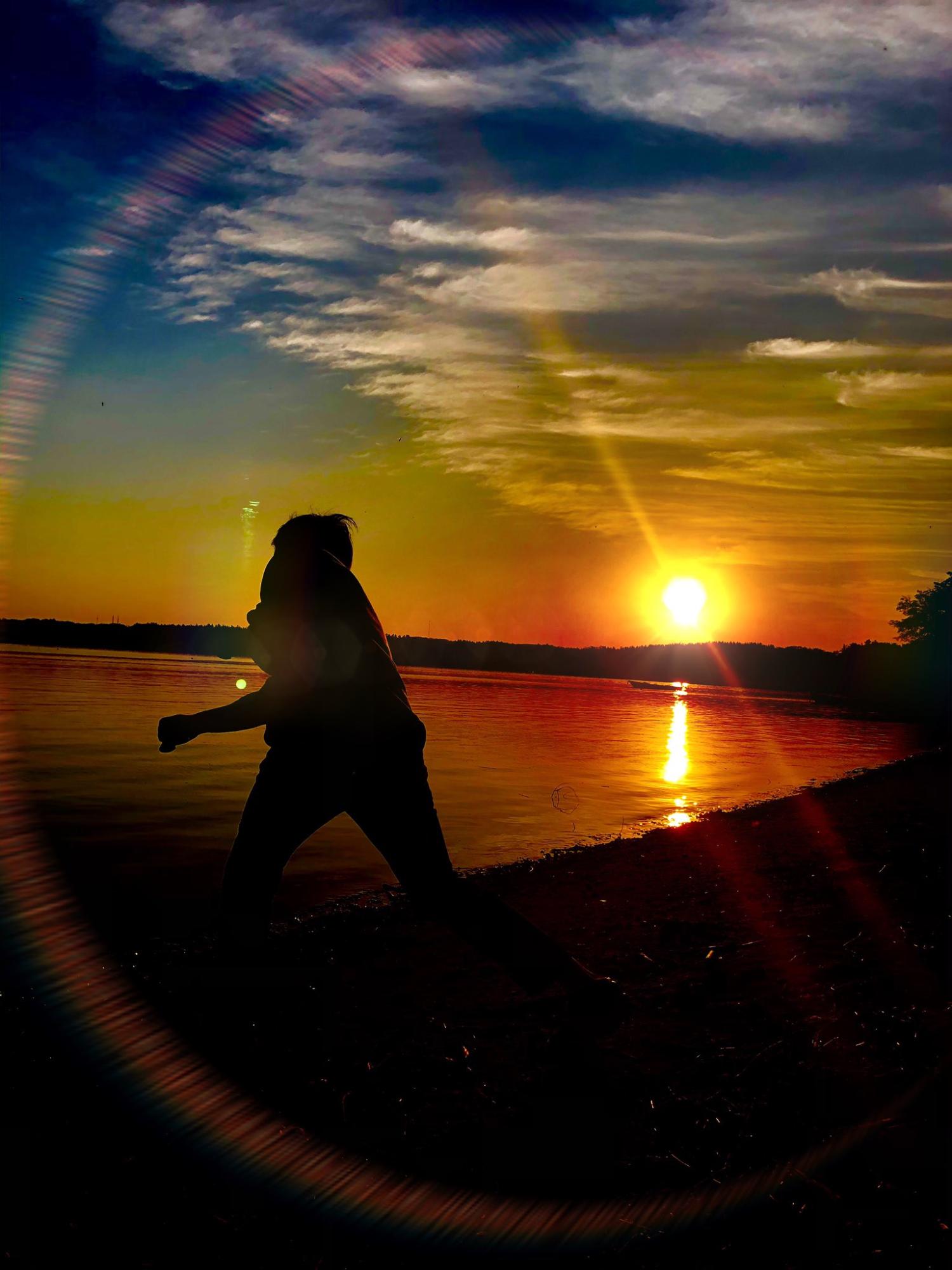湖畔に沈もうとしている夕日と、湖に石を投げた人を捉えた写真