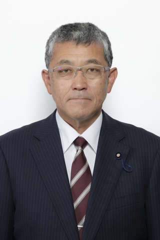 黒いストライプのスーツにエンジ色のネクタイをしめてシルバーのメガネをつけた森賀祐司さんが正面を向いている写真