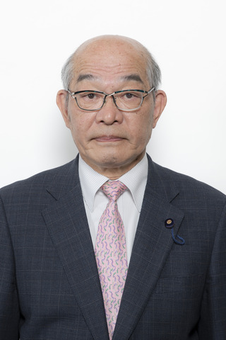 黒いチェックのスーツにピンク色のネクタイをしめてメガネをかけている岩原繁さんが正面を向いている写真
