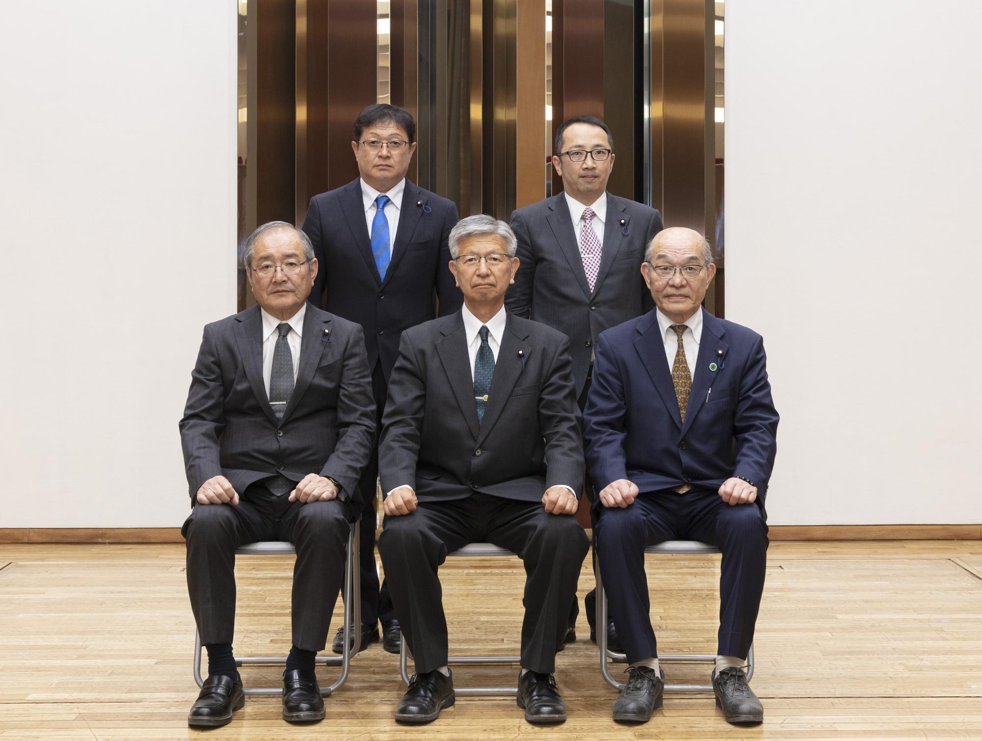 鈴木委員長を中心に、前3名が座り後ろ2名が立ち正面を向いている写真