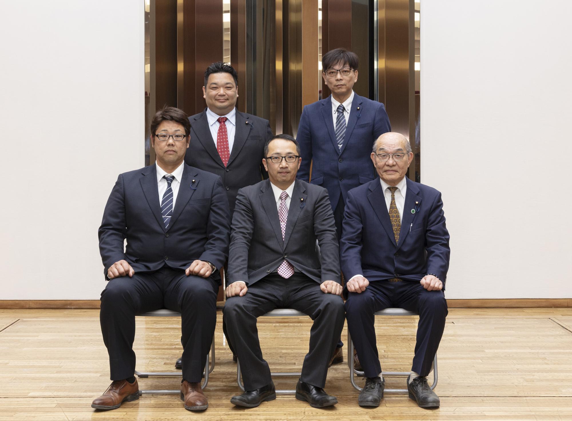 上地委員長を中心に、前3名が座り後ろ2名が立ち正面を向いている写真