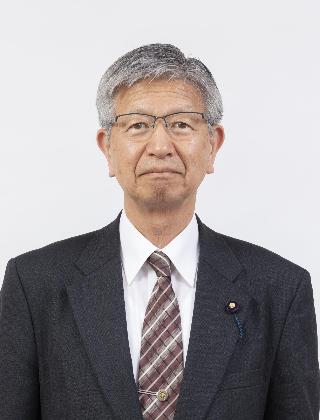 黒いスーツにチェックのネクタイをしめてメガネをかけた鈴木秀之さんが正面を向いている写真