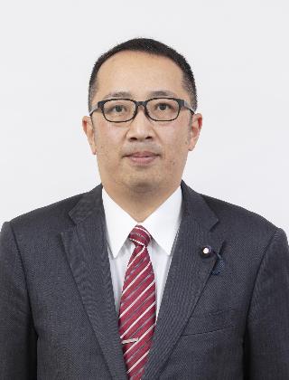 黒いスーツに赤色のストライプのネクタイをしめてメガネをかけている上地史隆さんが正面を向いている写真