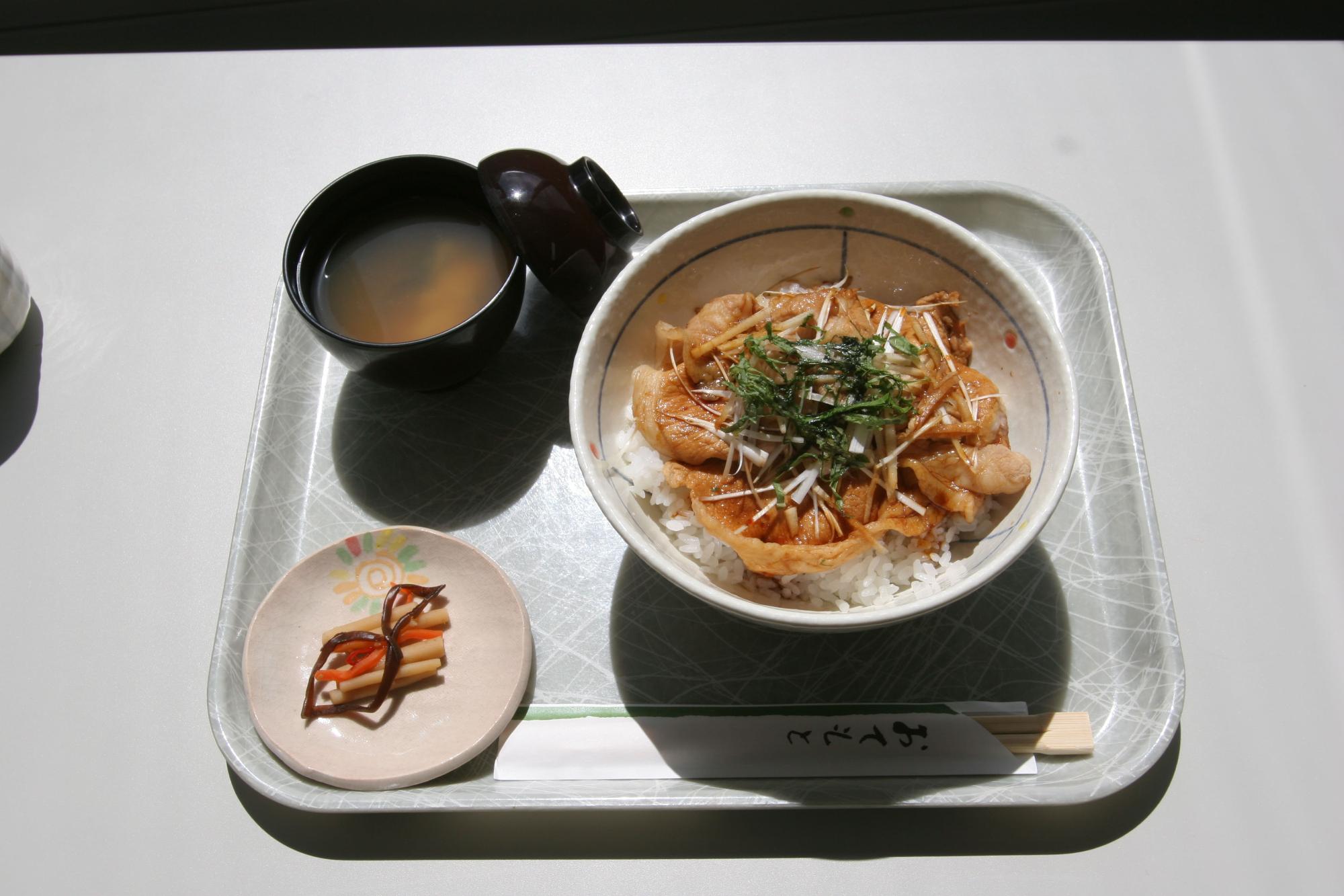 グレーのトレイの上に「さくら201」を使ったサクラ豚丼とみそ汁、漬物の小鉢がのっている写真