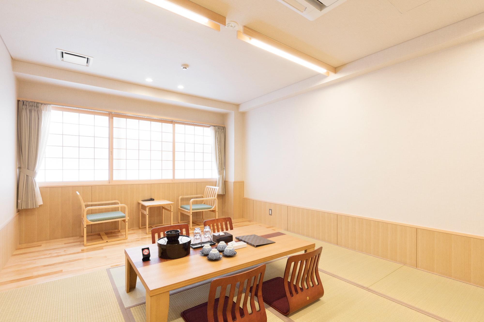 部屋の中央に茶器が並べられたローテーブルが置かれている和室室内の写真