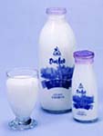 牛乳の入った大小ふたつの牛乳瓶とコップが並んでいる写真