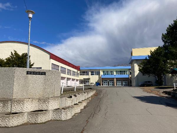 青空をバックに正面入り口を写した2階建てコンクリート造りの女満別中学校校舎の写真