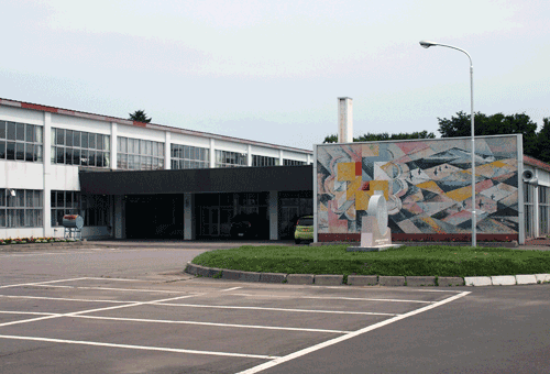 校舎に隣接する駐車場のロータリー前にモザイクアートの大きなパネルが設置されている写真