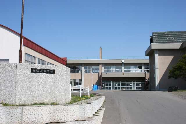 青空をバックに正面入り口を写した2階建てコンクリート造りの女満別中学校校舎の写真