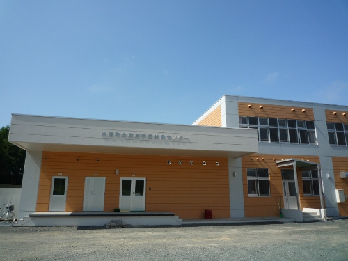 白い屋根に橙の壁の女満別学校給食センターの外観の写真
