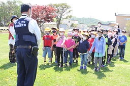 警察官と向かい合って立っている小学生たちの写真