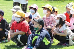 芝生に座っている小学生たちの写真