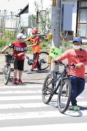 自転車を手押ししながら横断歩道を渡ろうとしている3人の男子小学生の写真