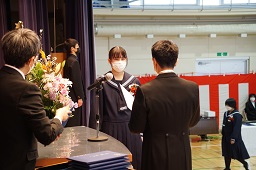校長先生から卒業証書を読み上げられている女子卒業生の写真