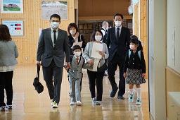 家族揃って学校の廊下を歩いている新一年生の男の子の写真