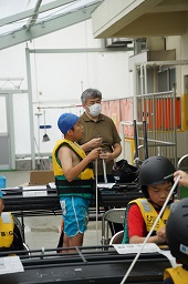 黄色い救命胴衣をつけている子どもたちとスタッフの男性の写真