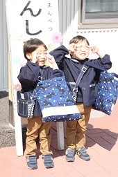 にゅうえんしきと書かれた立て看板の前でカバンを掛けながらポーズを取っている2人の男児の写真その2