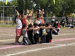 膝立ちで右腕を突き出している前列と両手を上げている後列の創作ダンスの様子の写真