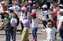 準備体操をしている紅白帽をかぶっている園児たちの写真