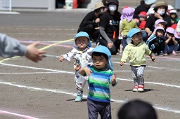 青い防止をかぶった3人の園児が歩いている様子の写真