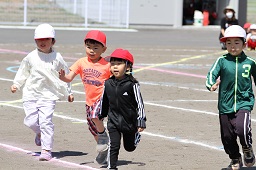 赤い帽子や白い帽子をかぶった4人の児童が駆け寄ってきている様子の写真