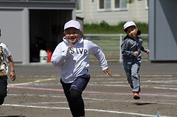 白い帽子をかぶっている男の子と女の子が走っている写真