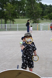 男の子が輪投げの台に向かって黄色い輪っかを投げている瞬間の写真