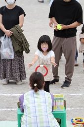 女の子が輪投げの台に向かって赤い輪っかを投げた瞬間の写真