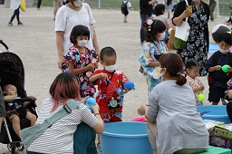 水ヨーヨー釣りで青い水風船を吊り上げた男の子とそれを見ているスタッフの写真