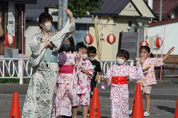 先頭で盆踊りをしている浴衣姿の女性とそれをまねして踊っている浴衣姿の子どもたちの写真