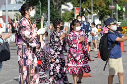 浴衣姿で盆踊りを踊っている子どもたちとその様子を見ている女性の写真