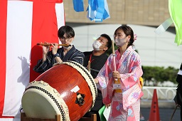 櫓の前で太鼓を叩いている浴衣姿の女性と横笛を吹いている男性の写真