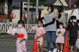 浴衣姿で盆踊りを踊っている子どもたちと普段着の女性の写真