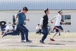 赤いはちまきをしている男子中学生2人と白いはちまきをしている男子中学生がコースを走っている写真