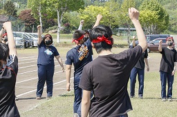 円陣を組んで右手を上げている赤いはちまきをしている中学生たちの写真