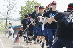 赤いはちまきをしている中学生たちと白いはちまきをしている中学生たちが長縄跳びを飛んでいる瞬間の写真