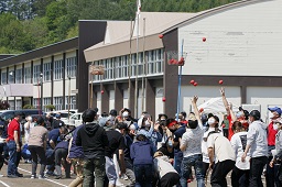 赤いはちまきをしている中学生たちと白いはちまきをしている中学生たちが玉入れをしている写真