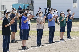 白いはちまきをしている中学生たちが拍手をしている様子の写真