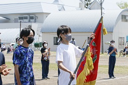 白いはちまきをしている男子中学生が赤い優勝旗を受け取っている写真