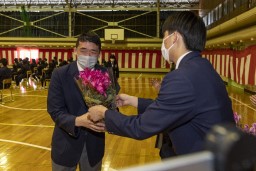 赤い花の花束を受け取っている卒業生の写真