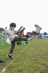 芝生の白線から男の子が履いているブーツを蹴り飛ばしている瞬間の写真