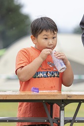 瓶詰めの牛乳をストローで飲み干そうとしている男の子の写真