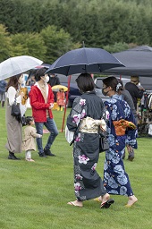 傘をさしている子ども連れの家族と浴衣姿の女性二人の写真