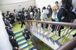 父母に見守られながら階段を降りる卒業生たちの写真