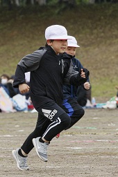 白い帽子をかぶった2人の男子小学生がグラウンドで走っている様子の写真