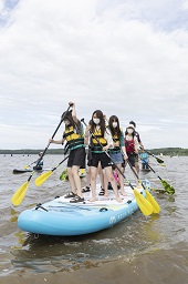 水面に浮いている大きなボードの上で立ち上がっている女性たちの写真