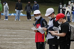 白い帽子の小学生2人と赤い帽子の小学生がマイクとメモ紙を持っている様子の写真