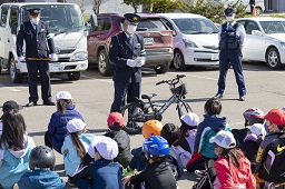 警察官の挨拶を座りながら聞いている小学生たちの写真